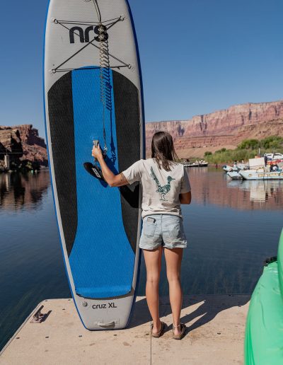 cliffdwellers general store (11) Woman holding paddleboard by lake with mountain backdrop