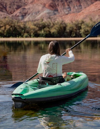 cliffdwellers general store (20) Woman kayaking on serene river with mountain backdrop